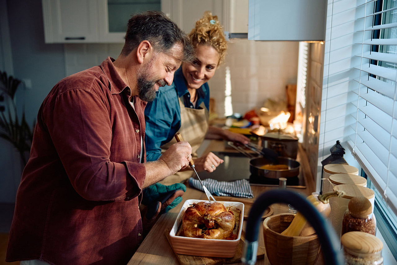 Happy couple preparing Thanksgiving turkey in the kitchen