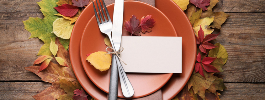 Festive table setting with autumn leaves and blank card on wooden background