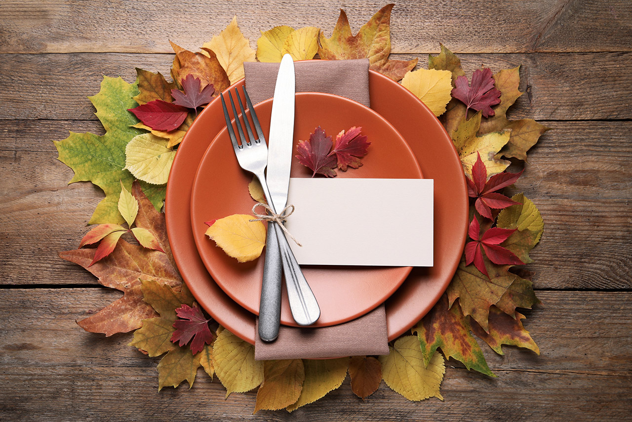 Festive table setting with autumn leaves and blank card on wooden background