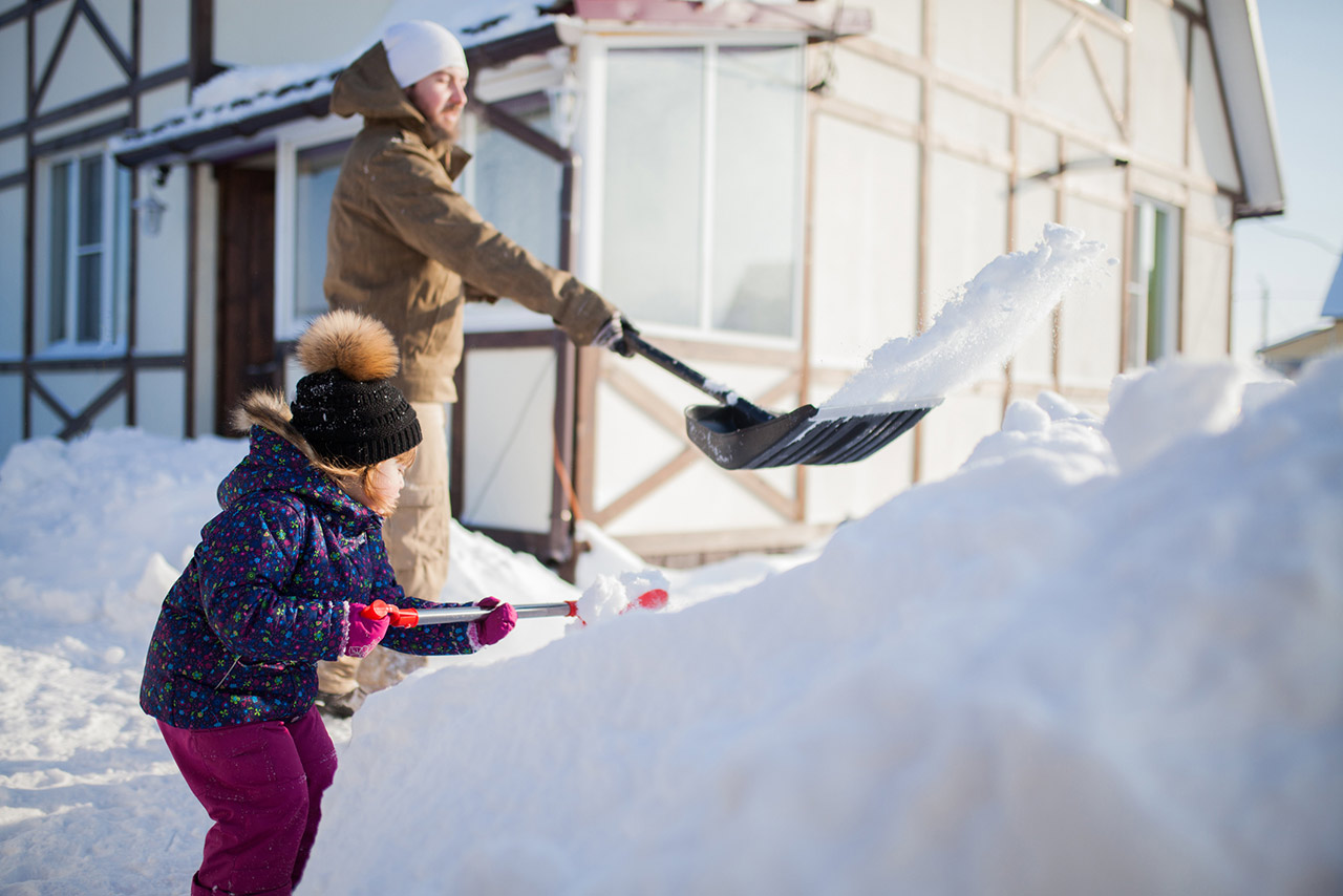 Little girl shoveling snow with her father