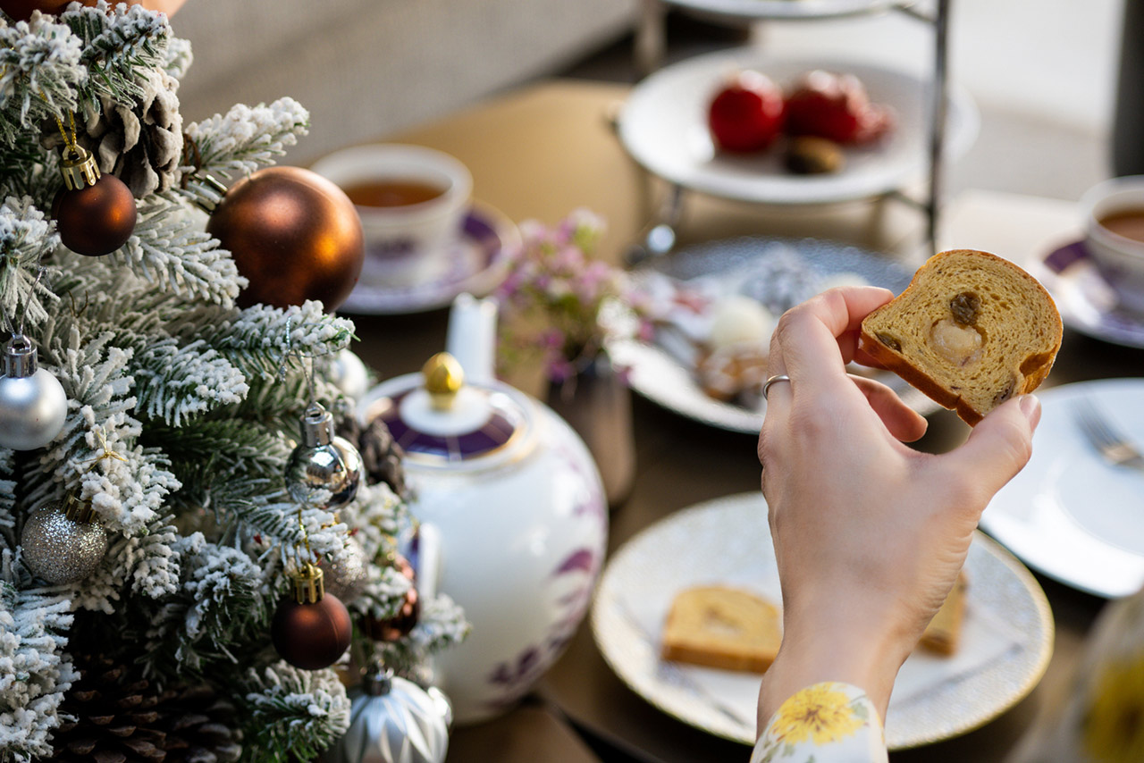 A beautifully set table, bread, tea sandwiches, and sweets are presented on a three-tiered tray