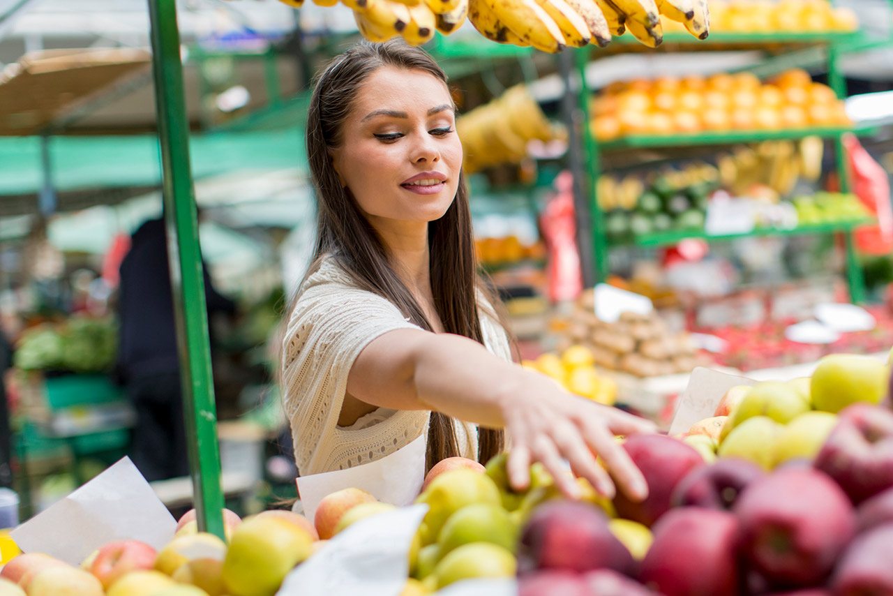 Young woman choosing apples at a farmers market