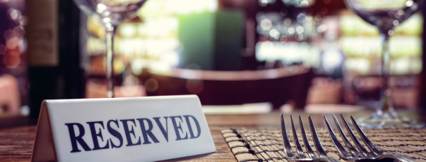 Restaurant reserved table sign with places setting and wine glasses ready for a party