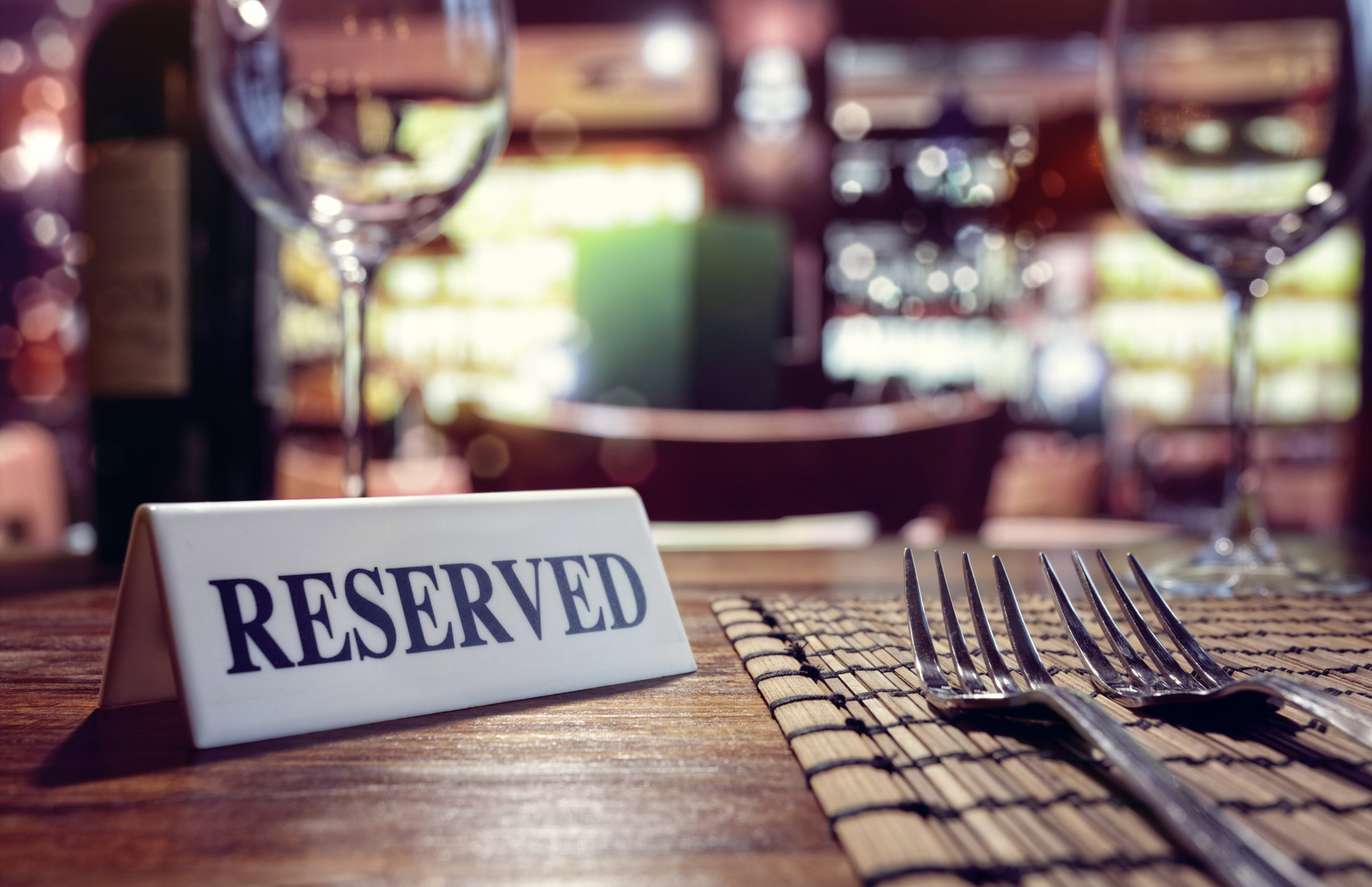 Restaurant reserved table sign with places setting and wine glasses ready for a party