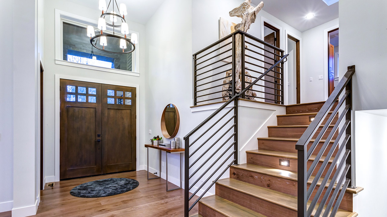 Chic entrance foyer with high ceiling and wide staircase with lights and contemporary railing