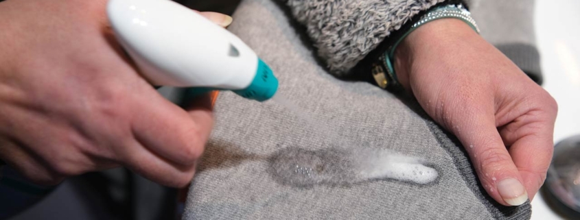 A pretreatment stain remover is applied to small spots on fabric, focusing on cleaning and preparing the garment for washing