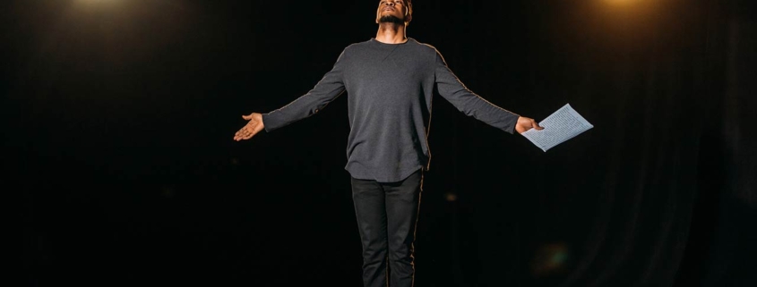 African American actor holding scenario and standing on stage during rehearsal
