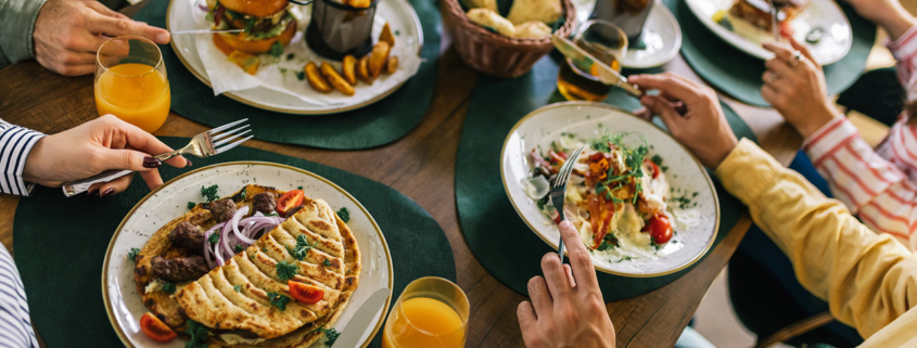 Group of happy friends eating lunch together in a restaurant
