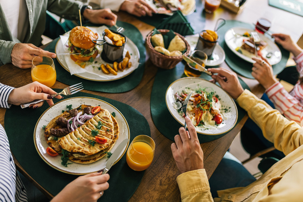 Group of happy friends eating lunch together in a restaurant