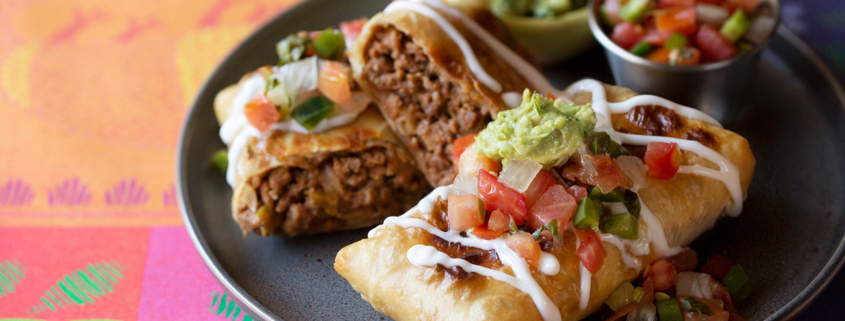 Tex-Mex Restaurant Chile Con Queso Dip in cast iron skillet with guacamole, salsa and tortilla chips stock photo