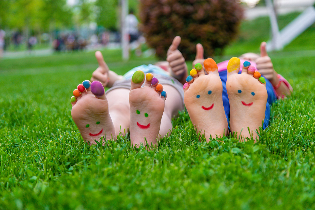 Children's feet with a pattern of paints smile on the green grass