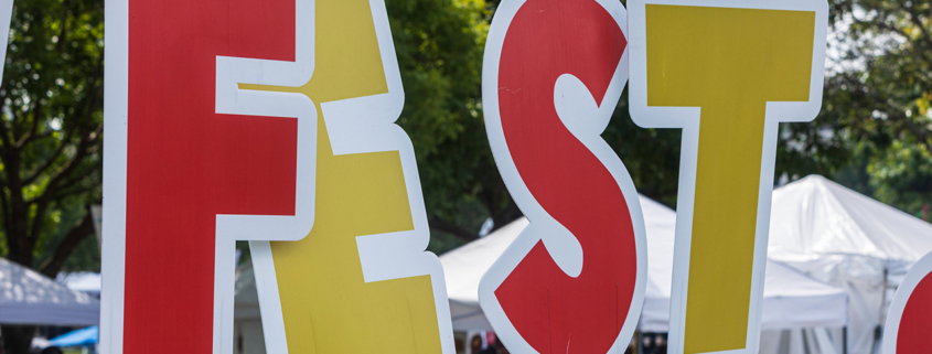 Large letters spelling FEST are planted in ground at fall festival