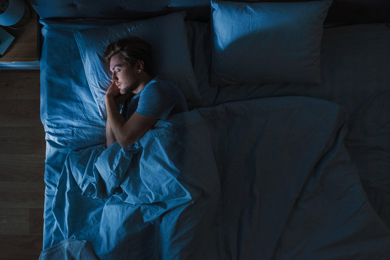Top View of Handsome Young Man Sleeping Cozily on a Bed stock photo