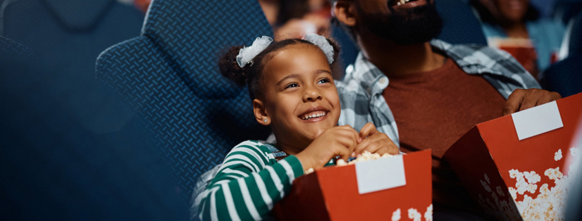 Happy black father and daughter enjoying in movie projection in theater stock photo