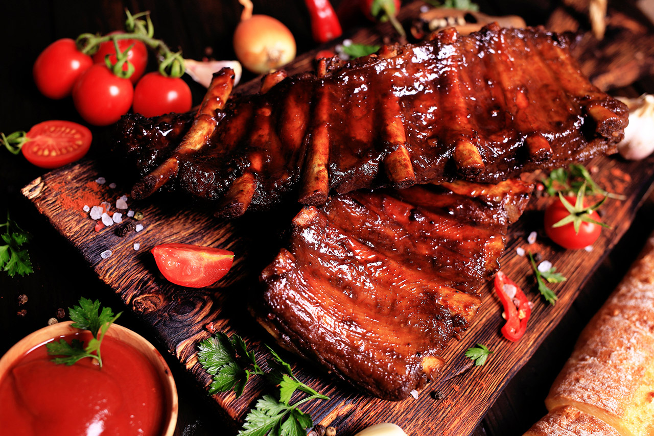 Grilled pork ribs with spices and vegetables on a wooden background stock photo