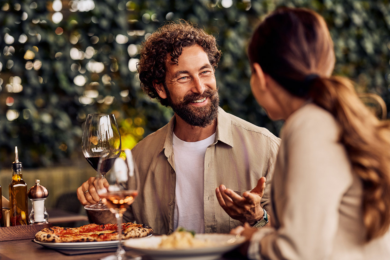 Happy Couple Enjoying Dinner Conversation at a Cozy Outdoor Restaurant stock photo