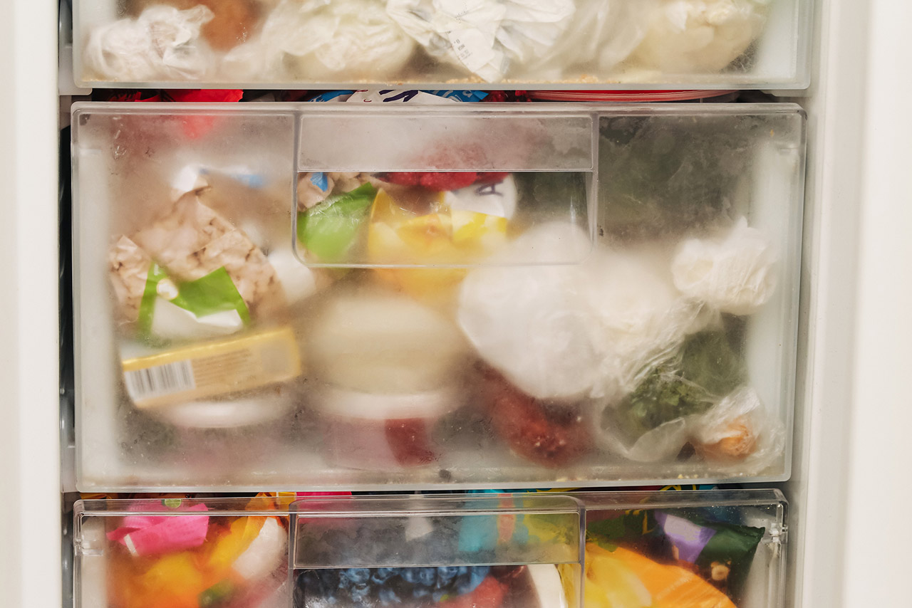 Overfilled freezer drawer packed with frozen food products stock photo